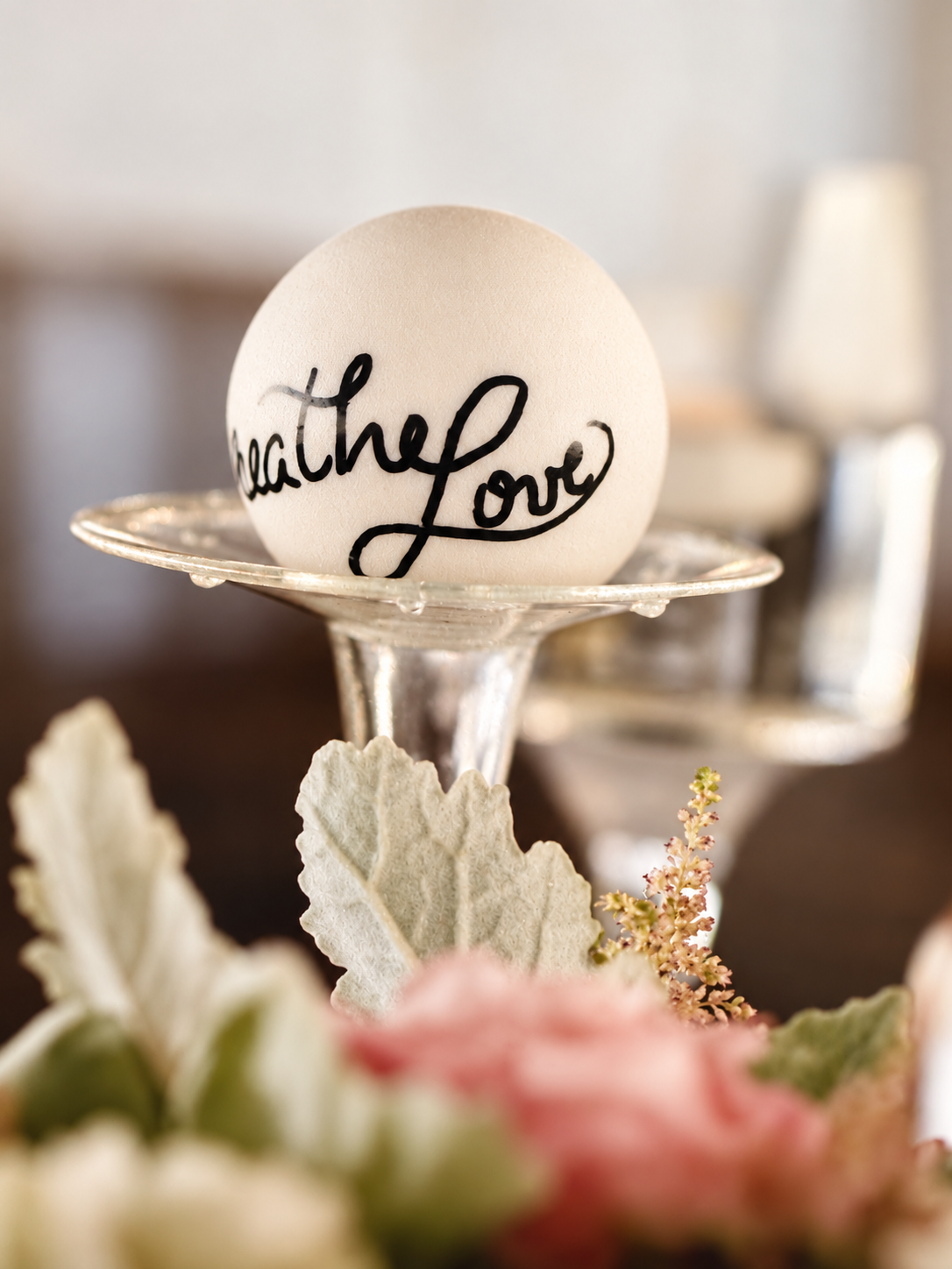 Wedding table detail bearing the handwritten words Breathe Love, surrounded by soft flowers.